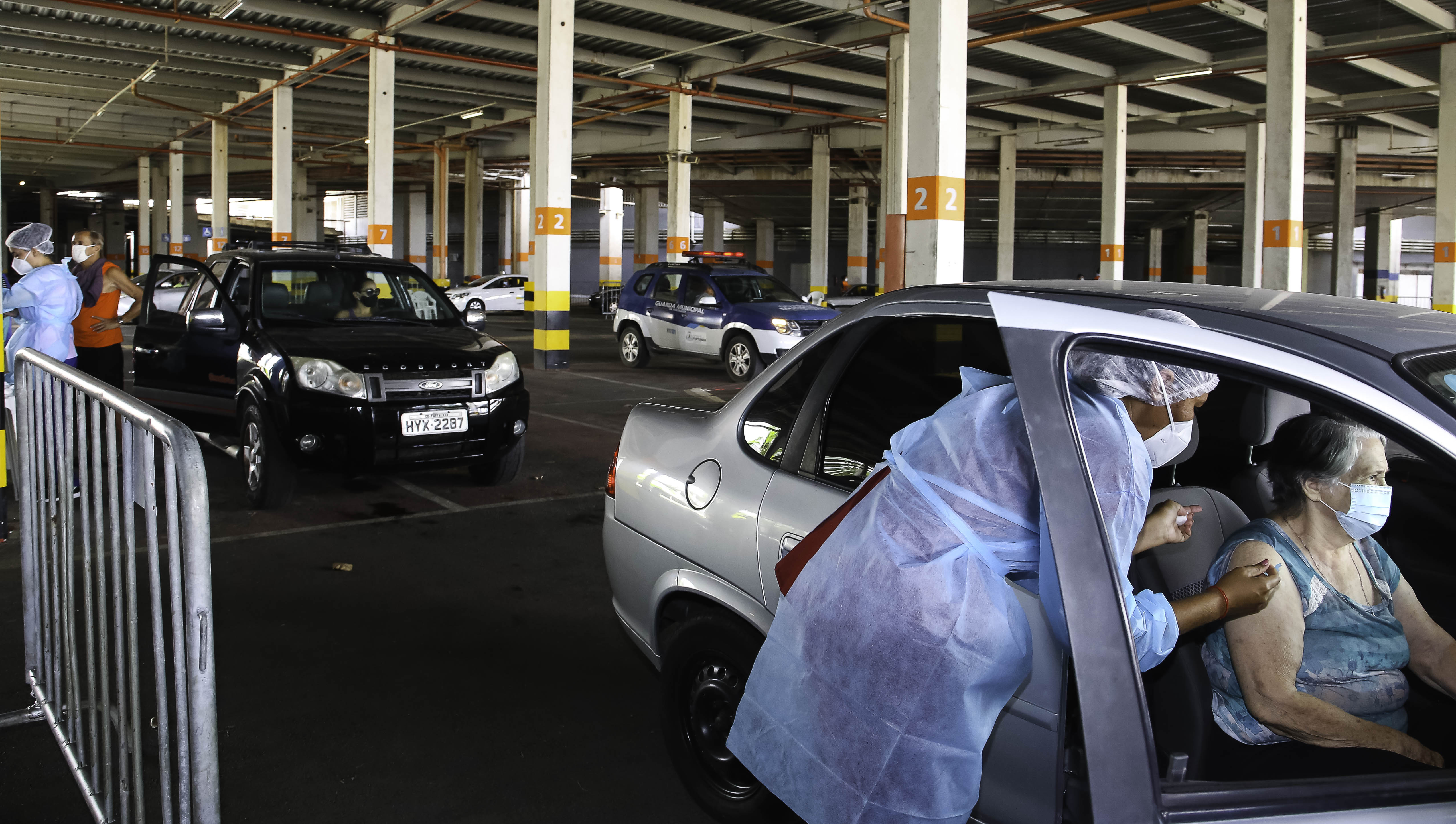 enfermeira vacina uma idosa dentro de um carro